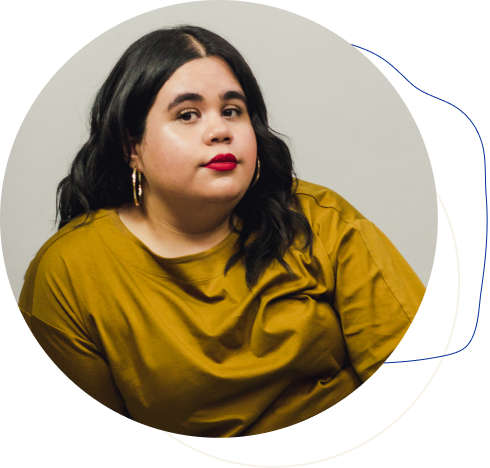 Photo of Lizelle, wearing red lipstick, gold hoop earrings and a mustard shirt.